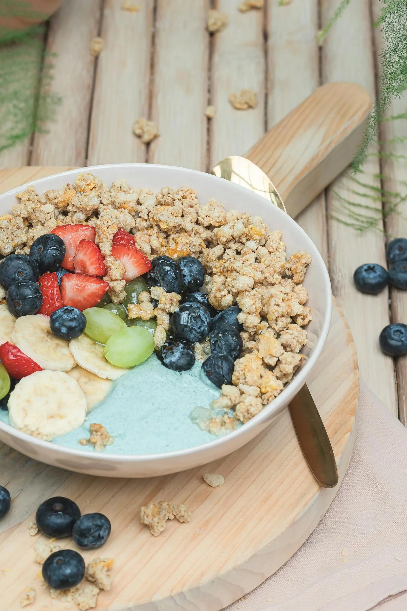 A vibrant breakfast bowl with fresh fruits, granola, and yogurt on a rustic table.